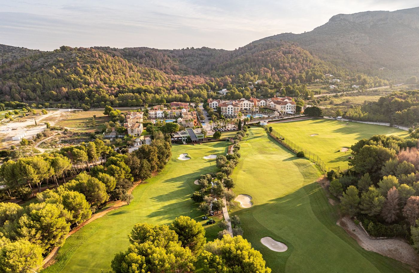 La Sella Golf Resort från ovan med fairways, bunkrar och hotellet i bergen